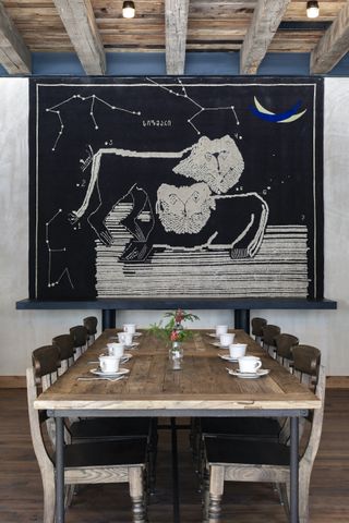 Long dining room table and chairs with black and cream astronomy art on the wall at Rooms Hotel Kokhta