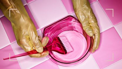 A pair of ghands holding a mixing bowl full of pink hair dye for learning how to dye your own hair at home 