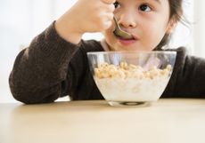 A little girl eating one of the healthiest cereal for kids from a bowl.