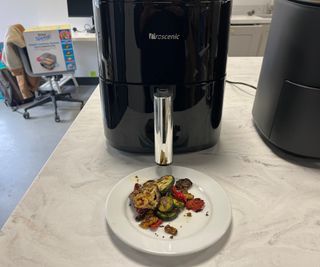 Roasted Mediterranean vegetables on a plate in front of the Prosenic T22 air fryer.