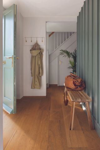 white painted hallway with pale green front door and panelling