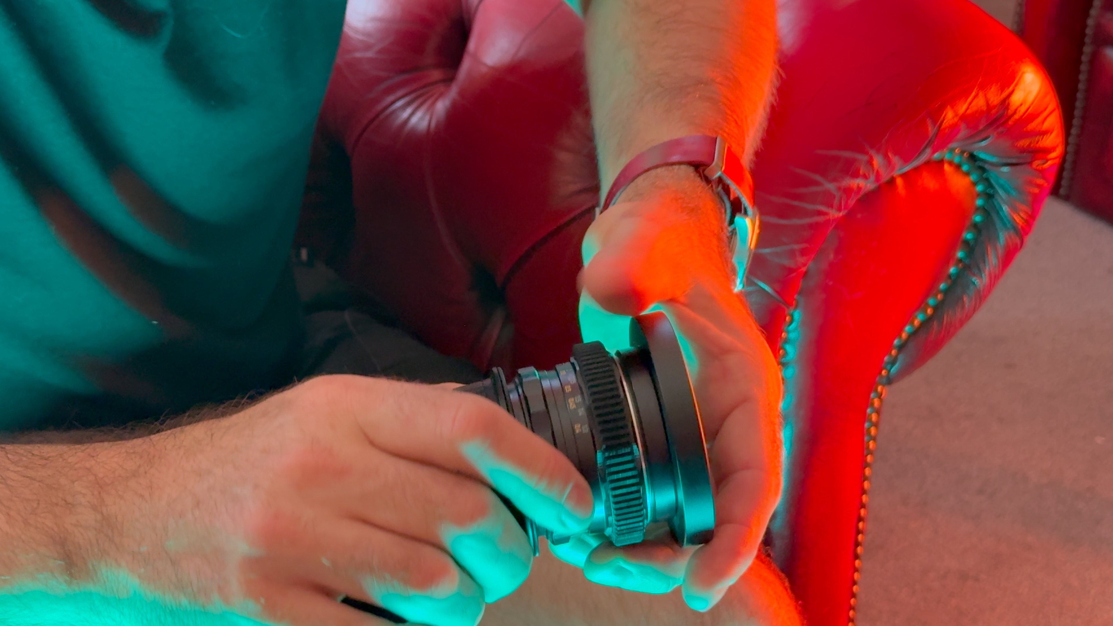 A person handling a camera lens lit by a red light