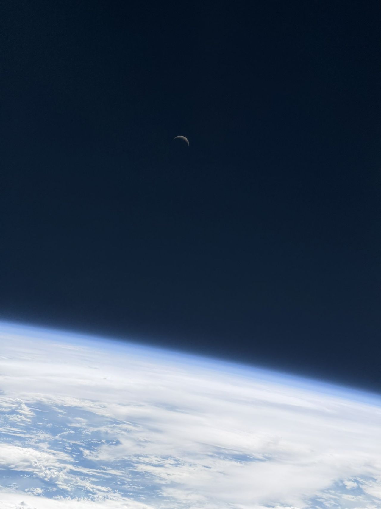 a crescent moon hangs over earth in space