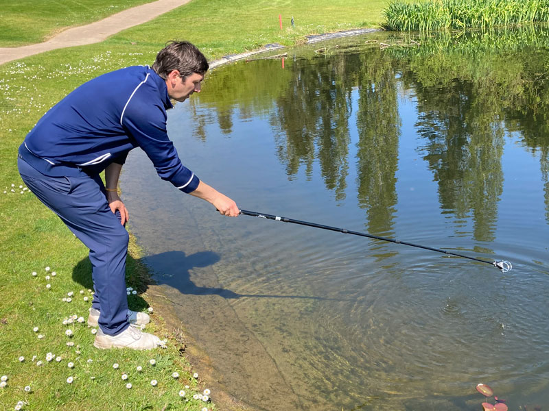 man using a golf ball retriever