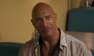 Dwayne Johnson smiling in a booth at a diner in Jumanji: Open World