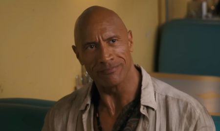 Dwayne Johnson smiling in a booth at a diner in Jumanji: Open World