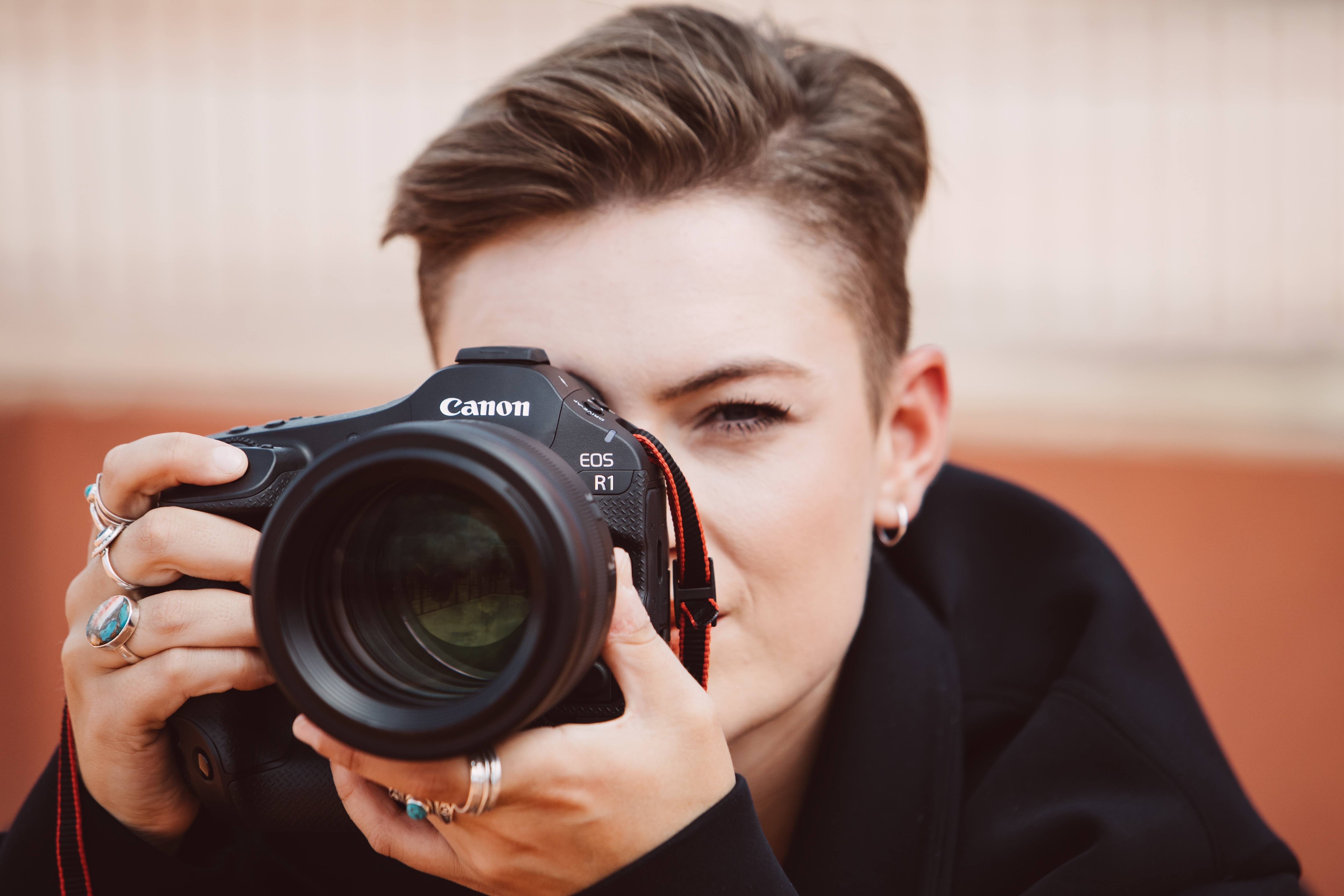 A person holding the Canon EOS R1 camera up to their eye