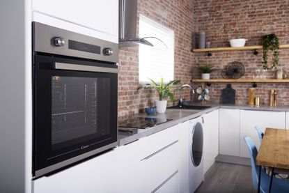 oven in a kitchen with exposed red brick walls 