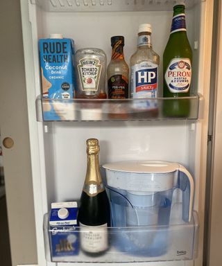 Inside of BEKO fridge containing ZeroWater water filter jug, organic cow's milk, organic coconut milk drink, Peroni beer and condiments