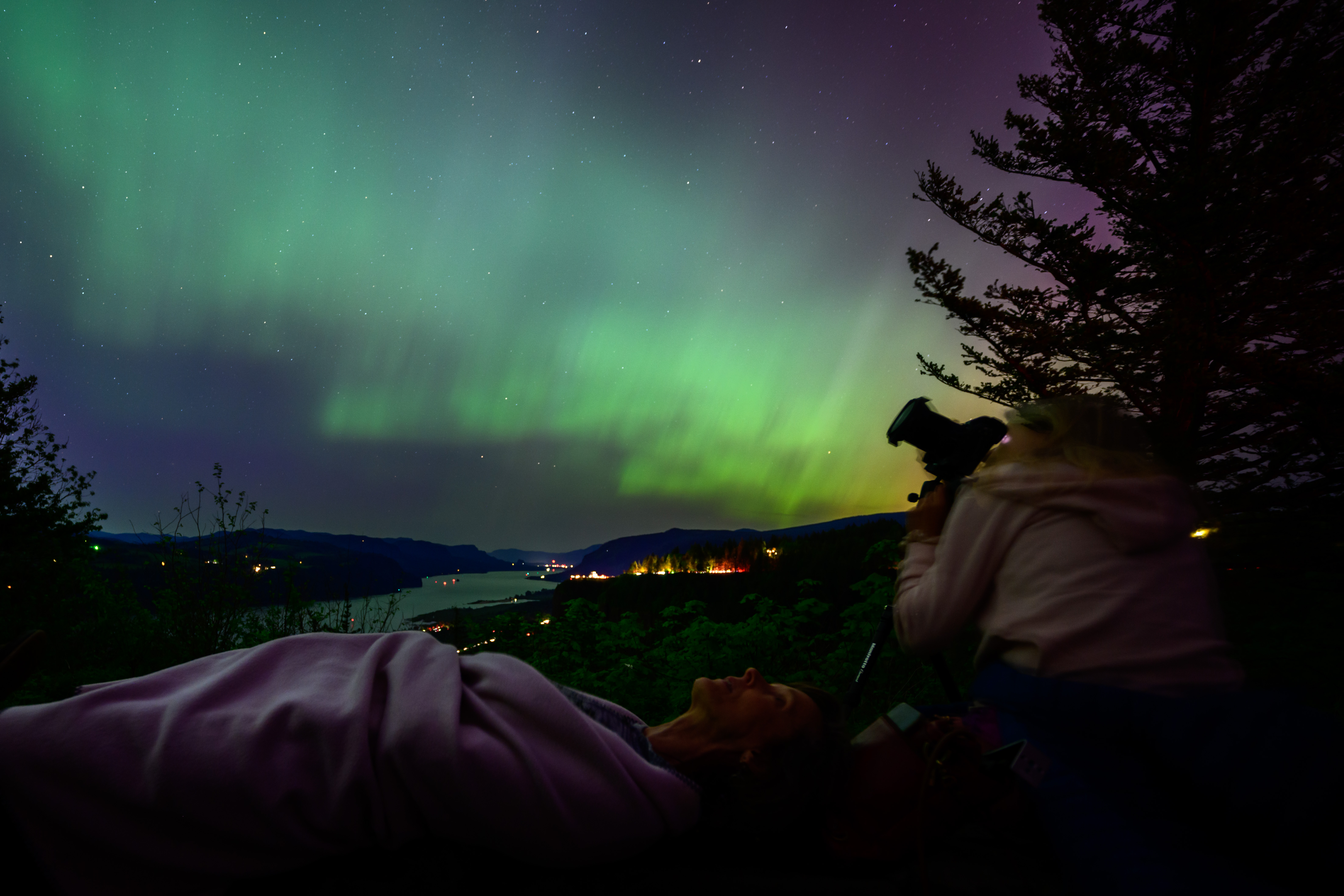 Kathryn Richer (left) and her friend Andrea gaze upon the Northern Lights at Chanticleer Point Lookout on the Columbia River Gorge in the early morning hours of May 11, 2024 in Latourell, Oregon.