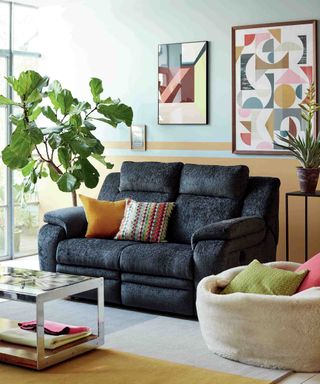 A dark charcoal sofa in a living room with bright pastel framed wall art