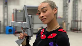 Intergalactic: The Heretic Prophet actor Tati Gabrielle smiles while brandishing prop weapon