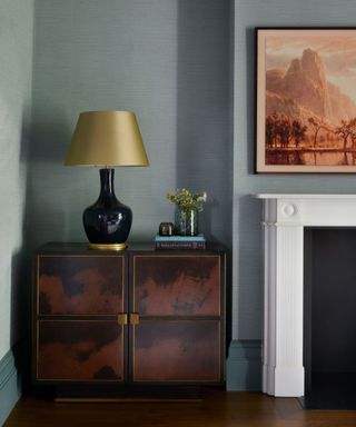 corner of room with muted blue walls, sideboard and gold table lamp