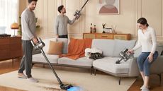 Three people using the Dreame R20 cordless vacuum in different configurations, vacuuming the rug, sofa, and picture fram in a brown living room with warm, neutral colors.