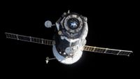 a black spacecraft with a white rear and extended solar arrays flies through the blackness of space