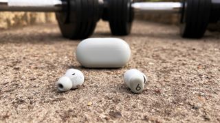 Beats Solo Buds on the ground in front of a pair of dumbbells