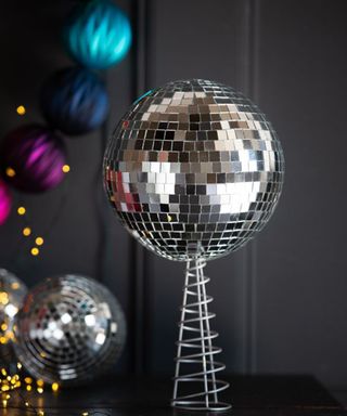 Disco ball Christmas tree topper with black wall background and colored baubles