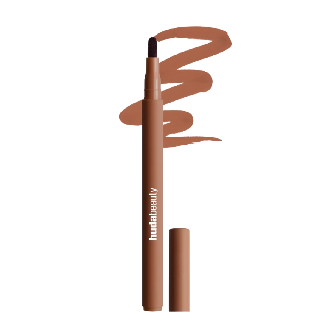 A product shot of the Huda Beauty Lip Contour Stain in shade Toasty Brown, alongside a swatch of the liner and on a white background