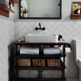 A basin unit in a bathroom with tiled walls, a square basin and mirror