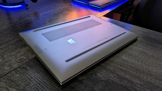 Image of the HP ZBook Firefly 14" (G10) flipped over on a desk, showing the bottom panel, vent, and rubber feet.