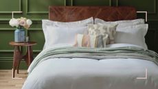 Green bedroom with wooden bed dressed with crisp white bedding