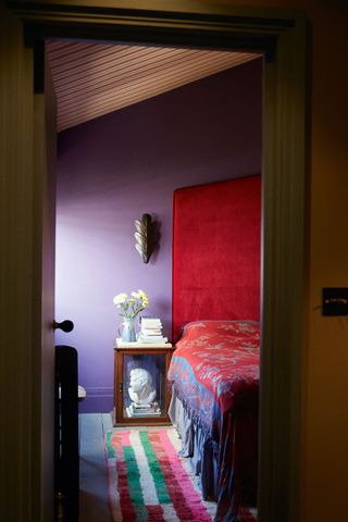 Purple bedroom with red bed by Rachel Chudley