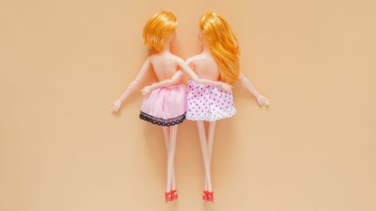 Sex doll? Two female dolls naked on top hugging each other with beige background.