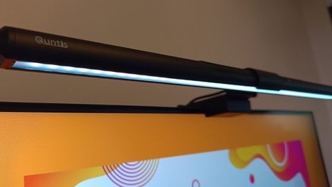 A black Quntis ScreenLinear Pro+ lightbar set upon the top of a monitor