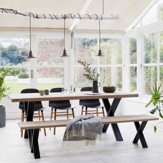 Rust Collections Xavier oak dining table on raw steel legs in white dining room with a wall of windows