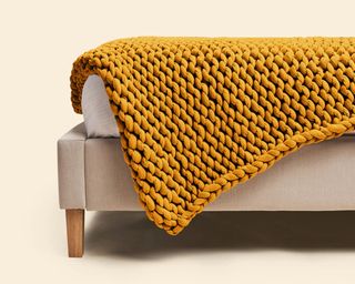 Best weighted blanket in yellow knit draped over grey sofa