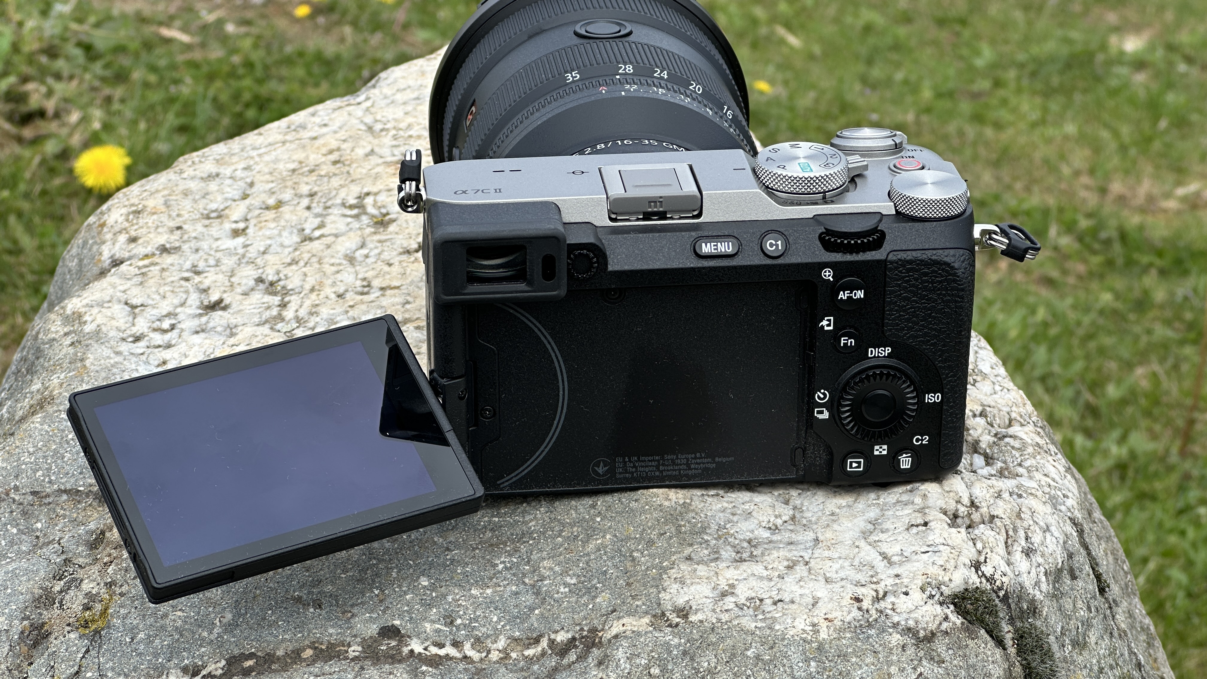 Sony A7C II mirrorless camera with vari-angle screen flipped out to the side outside on a rock with Sony FE 16-35mm F2.8 GM II lens attached