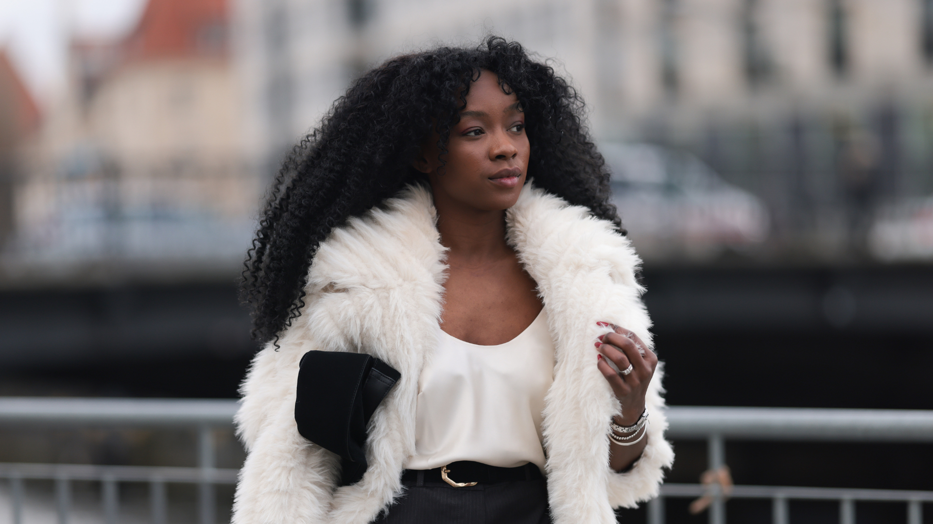 Lilian Litehiser seen wearing Beaumont white fake fur midi coat, white cotton top, Topshop grey pinstripe micro shorts, black leather / gold belt and Massimo Dutti black suede leather clutch bag, during Berlin Fashion Week AW25 on January 31, 2025 in Berlin, Germany
