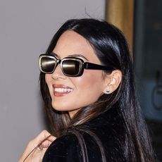 Olivia Munn wearing a black coat, brown bag, and black heels