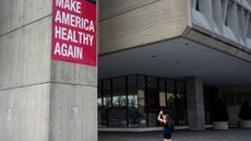 A woman takes a photo of the Make America Healthy Again sign hanging outside the Department of Health and Human Services in Washington on Monday, September 15, 2025