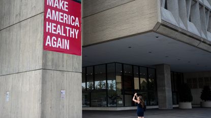 A woman takes a photo of the Make America Healthy Again sign hanging outside the Department of Health and Human Services in Washington on Monday, September 15, 2025