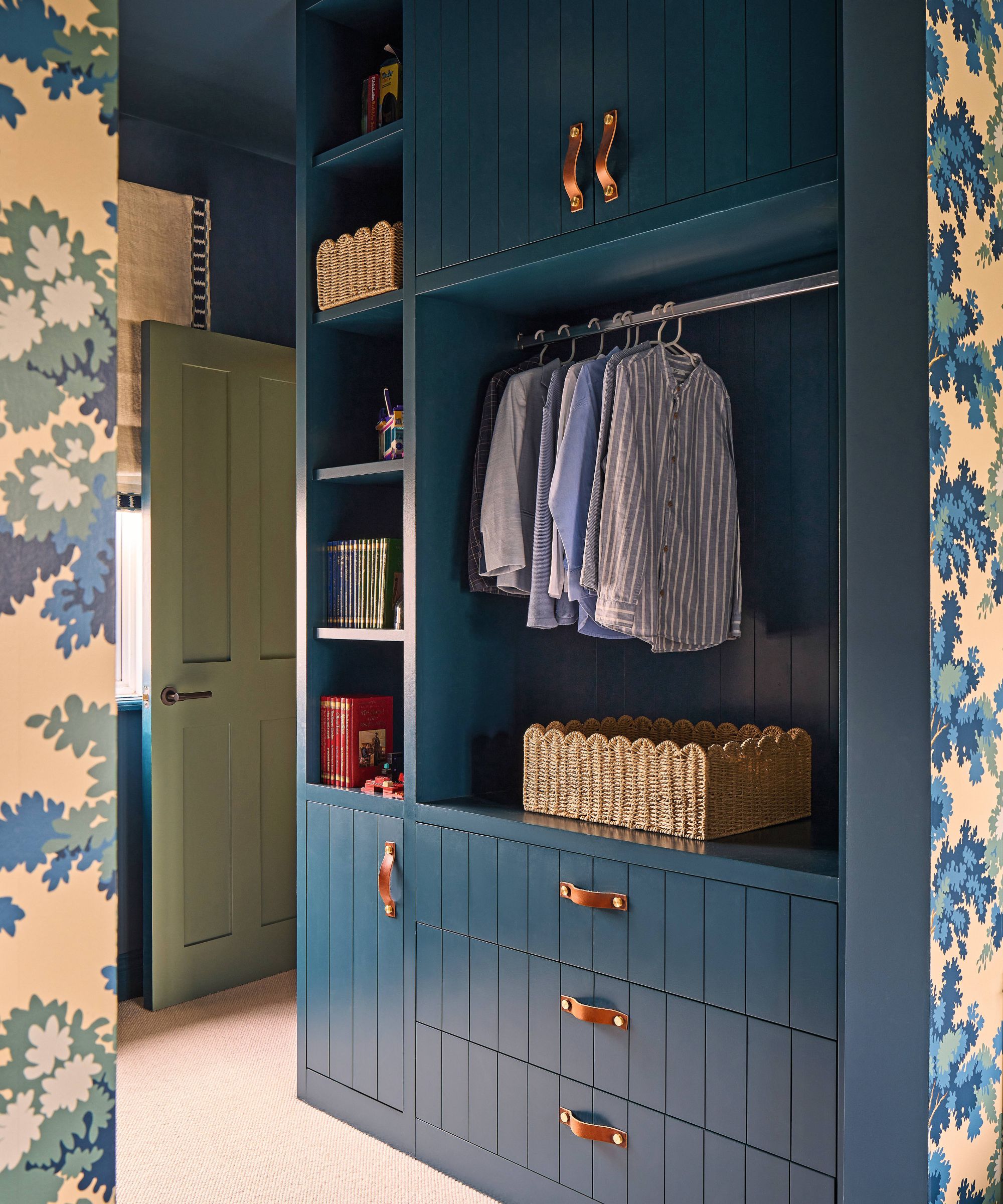 a kids bedroom dressing area with navy blue custom wardrobes and floral wallpaper