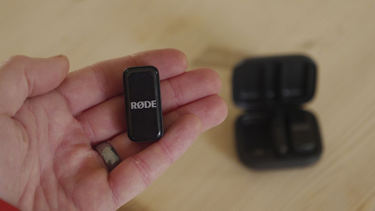 Rode Wireless Micro transmitter in the hand, wooden table background