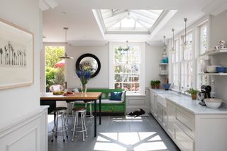 light bright white kitchen with skylight and large windows a breakfast bar and green bench