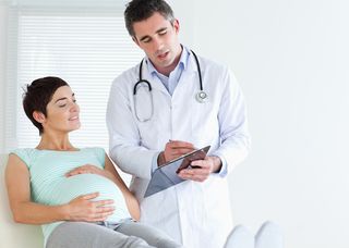 A pregnant woman talks with her doctor.