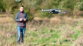 A man flying a DJI drone in a field