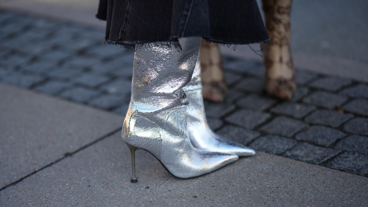 Marianne Theodorsen wears a black denim ripped asymmetric skirt, silver shiny leather pointed heels knees boots / high boots, outside Mark Kenly Domino Tan, during the Copenhagen Fashion Week Autumn/Winter 2023 on February 02, 2023 in Copenhagen, Denmark