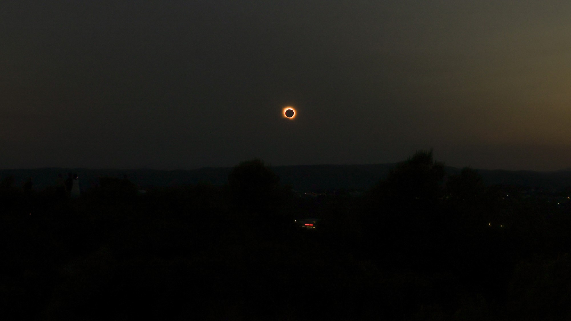 the sun is blocked by a dark orb in a dusky, grey sky