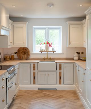 small kitchen with off white units, walls and light wooden floor and worktops