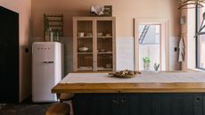 A oink and navy blue kitchen with a white Smeg fridge
