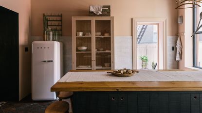 A oink and navy blue kitchen with a white Smeg fridge