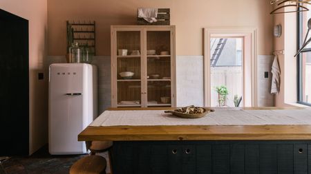 A oink and navy blue kitchen with a white Smeg fridge