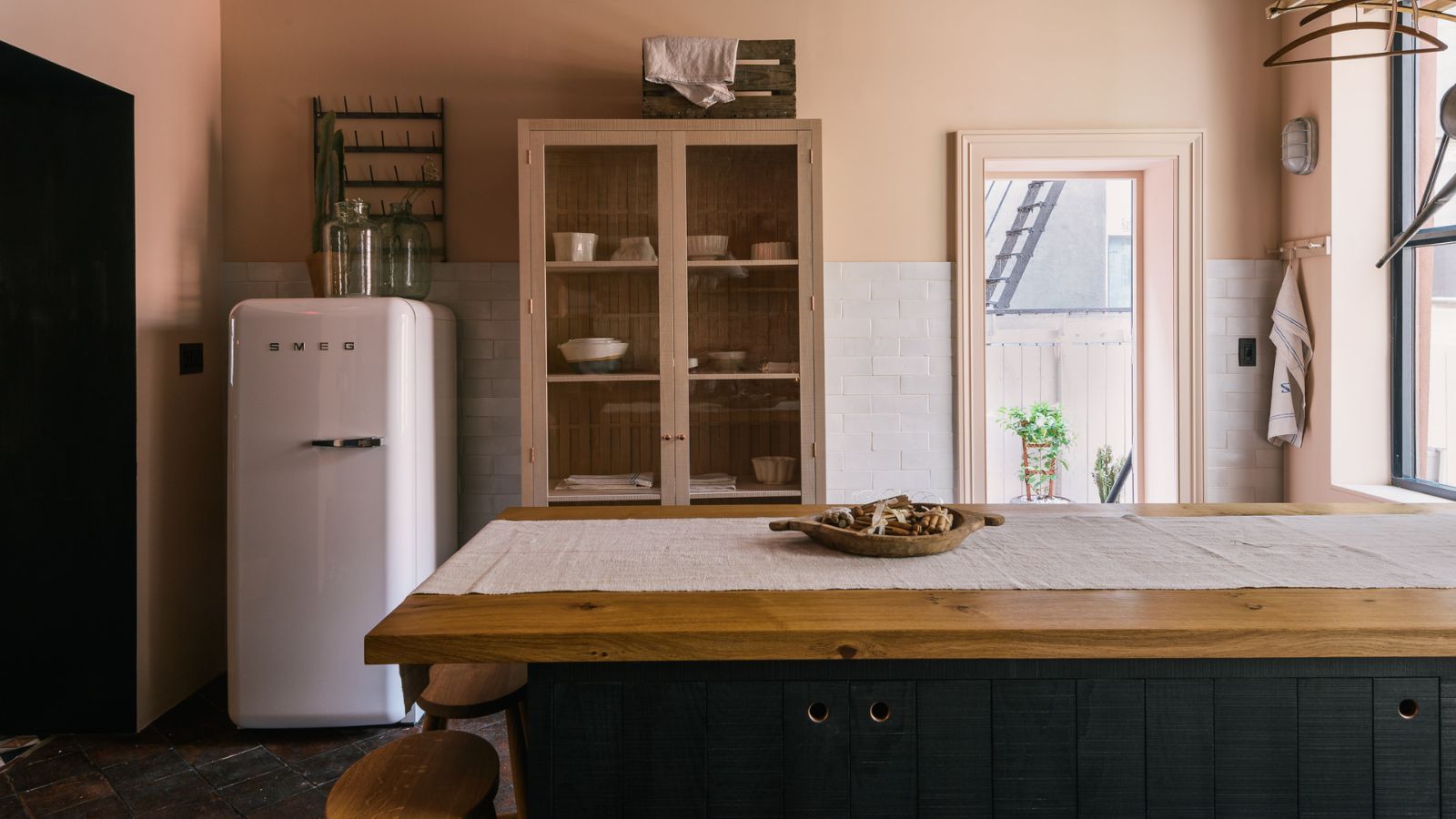 A oink and navy blue kitchen with a white Smeg fridge