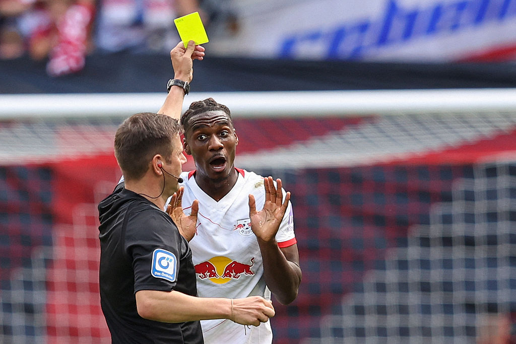 Leipzig's Dutch midfielder #06 Ezechiel Banzuzi is shown a yellow card by German referee Frank Willenborg during the German first division Bundesliga football match between RB Leipzig and 1. FC Heidenheim 1846 in Leipzig on August 30, 2025.