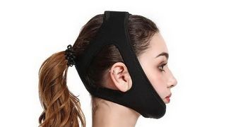 A side profile of a woman wearing a black jaw strap that straps around her whole head