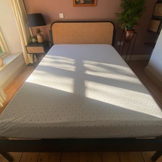 The Zinus Green Tea Memory Foam mattress being tested in a bedroom with a rattan headboard and pink walls